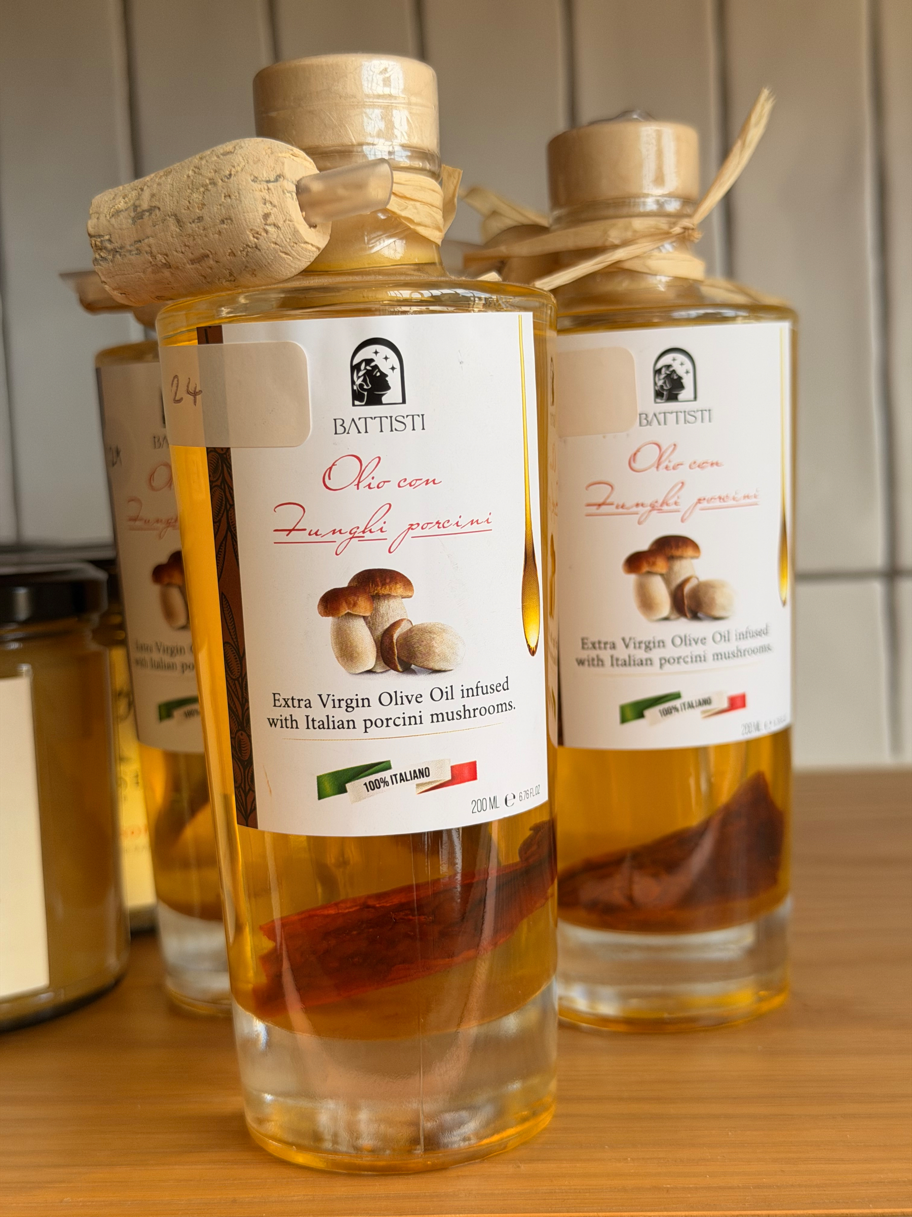 Bottles of extra virgin olive oil infused with Italian porcini mushrooms are displayed with cork toppers and labels.Olive oil bottle with cork, infused with porcini mushrooms.